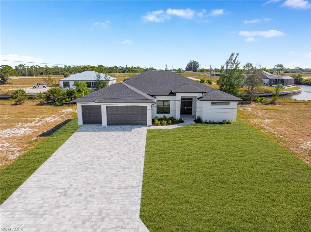 View of front of property with a front lawn, decorative driveway, an attached garage, and a shingled roof