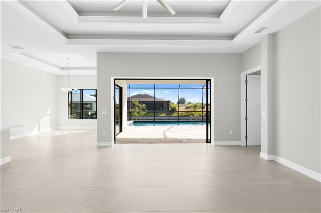 Spare room featuring a tray ceiling, a ceiling fan, a chandelier, and light tile patterned floors