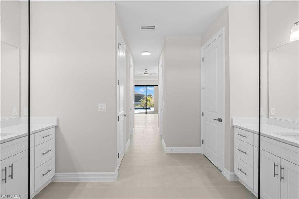 Bathroom featuring two vanities, light tile patterned flooring, and ceiling fan