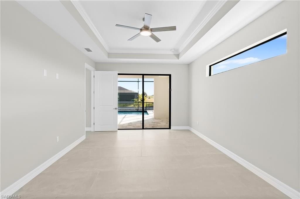 Spare room with plenty of natural light, a tray ceiling, ceiling fan, ornamental molding, and a sunroom