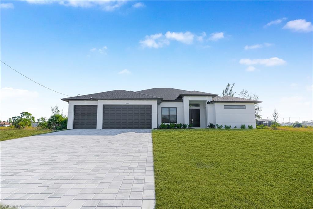 Prairie-style house with a front lawn, decorative driveway, a garage, and stucco siding