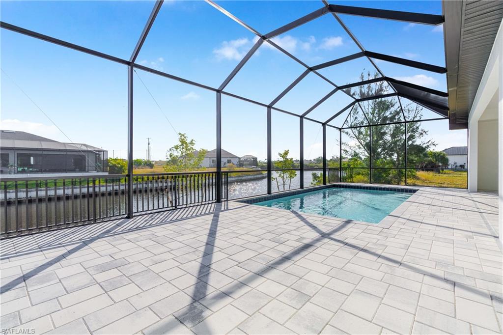 Swimming pool featuring a water view, a sunroom, a patio, and glass enclosure