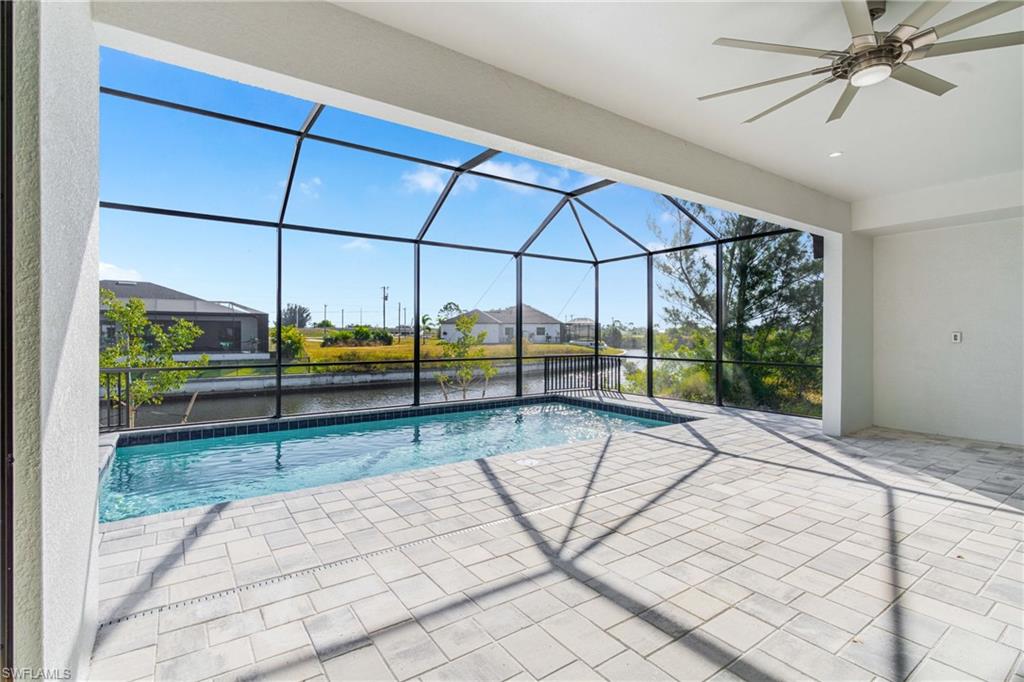 Outdoor pool with a lanai, a sunroom, a patio, a ceiling fan, and a water view