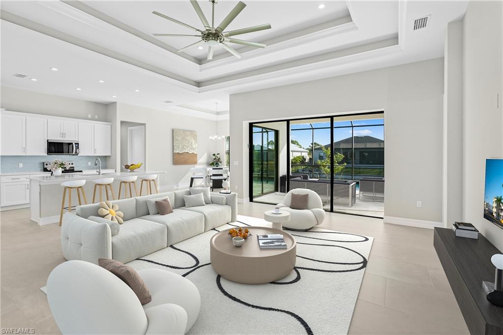 Living room featuring recessed lighting, a raised ceiling, a chandelier, and ceiling fan