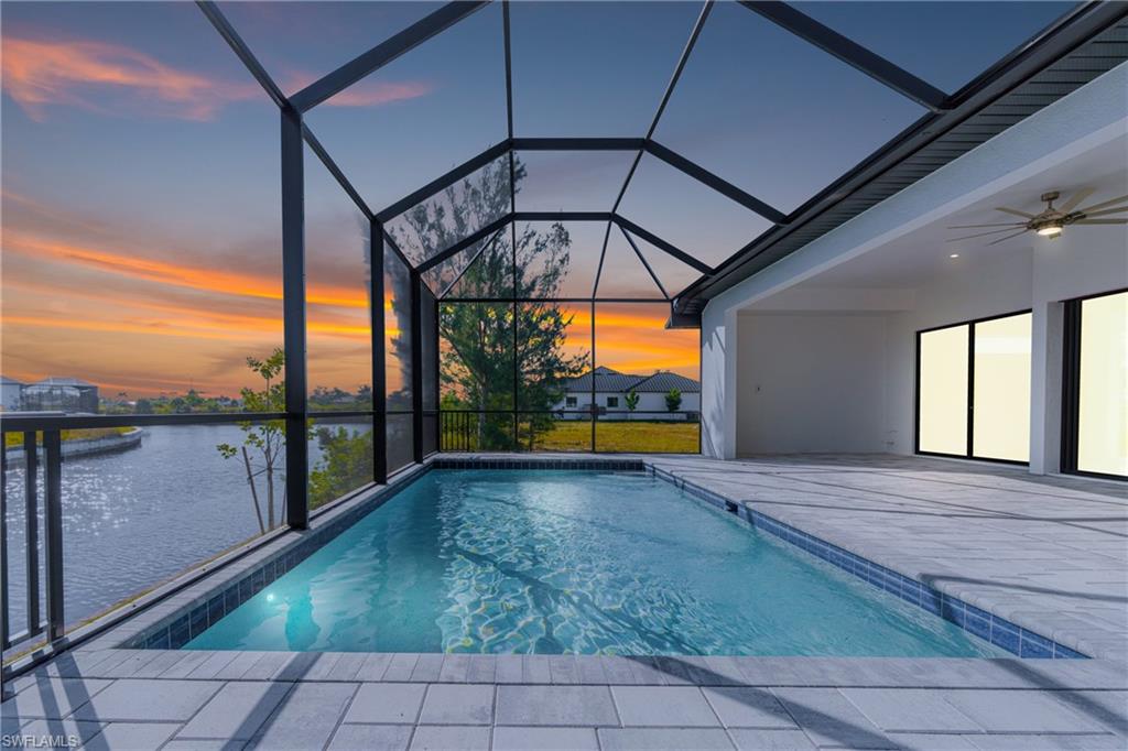 Outdoor pool featuring ceiling fan, a lanai, a sunroom, and a water view