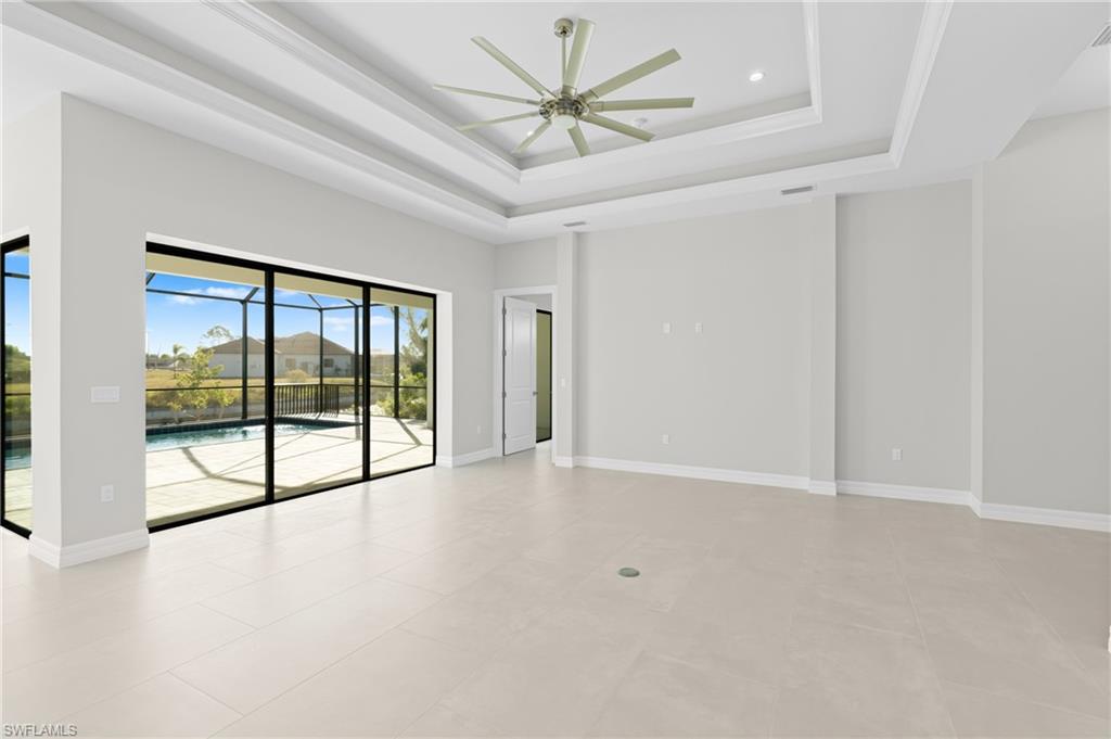 Empty room featuring a raised ceiling, a ceiling fan, and a sunroom