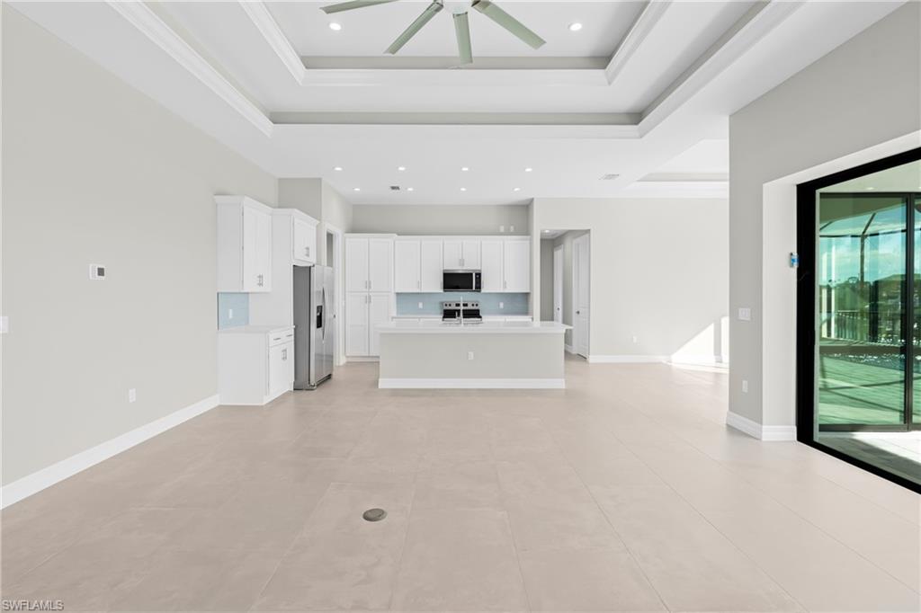 Unfurnished living room featuring a tray ceiling, ceiling fan, light tile patterned flooring, and recessed lighting