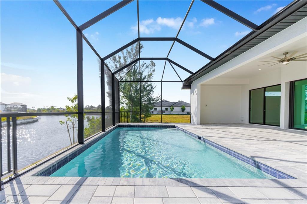 Swimming pool with ceiling fan, a sunroom, a patio area, a water view, and a lanai