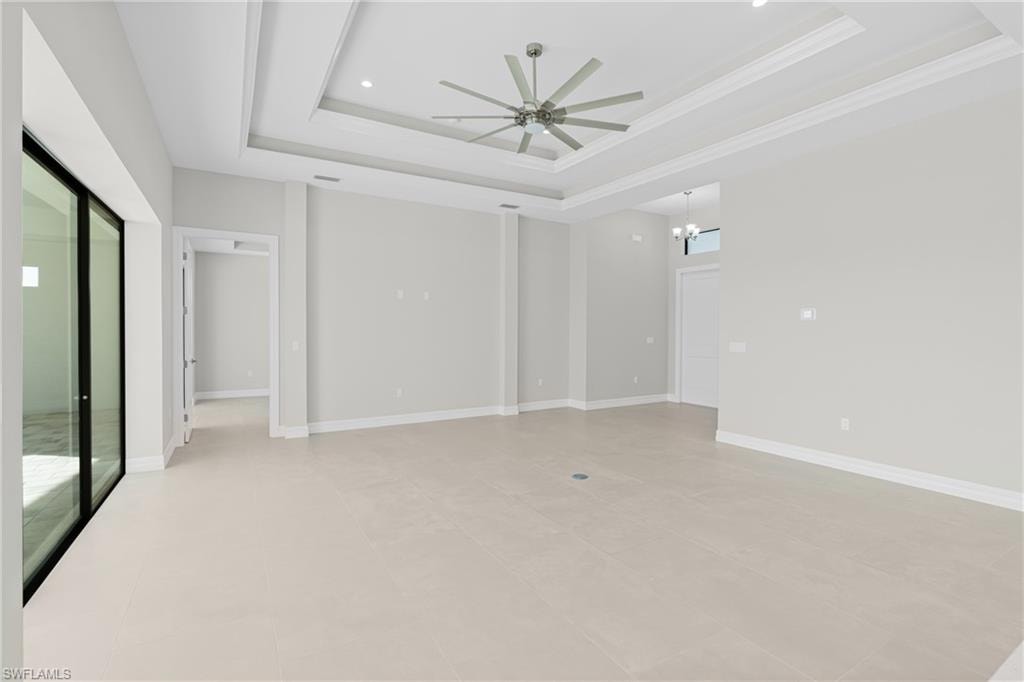 Unfurnished bedroom featuring a tray ceiling, ceiling fan, and a chandelier