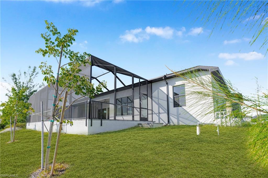 Back of property with a sunroom, a yard, and a lanai