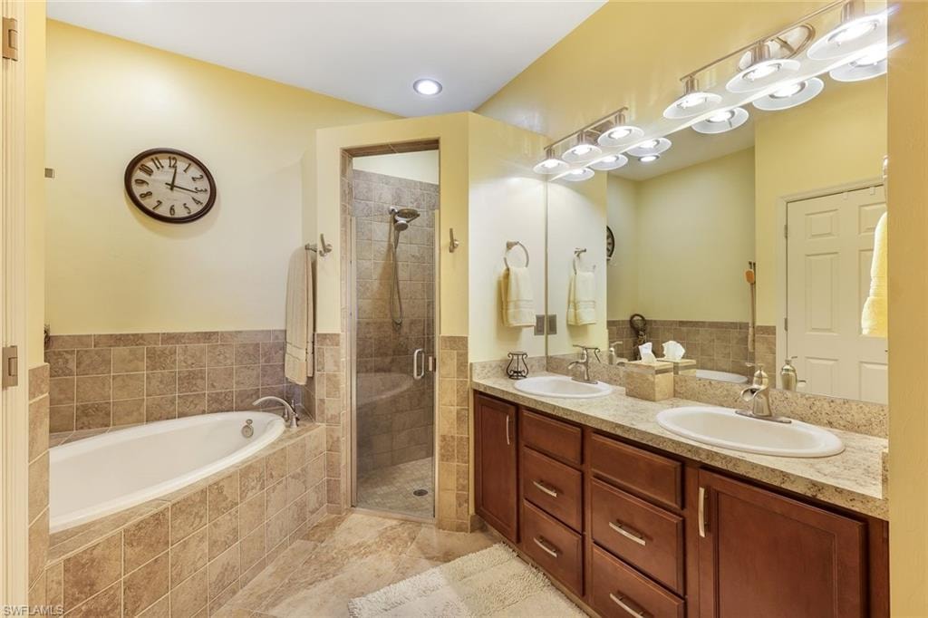 Bathroom with a garden tub, double vanity, a shower stall, and recessed lighting