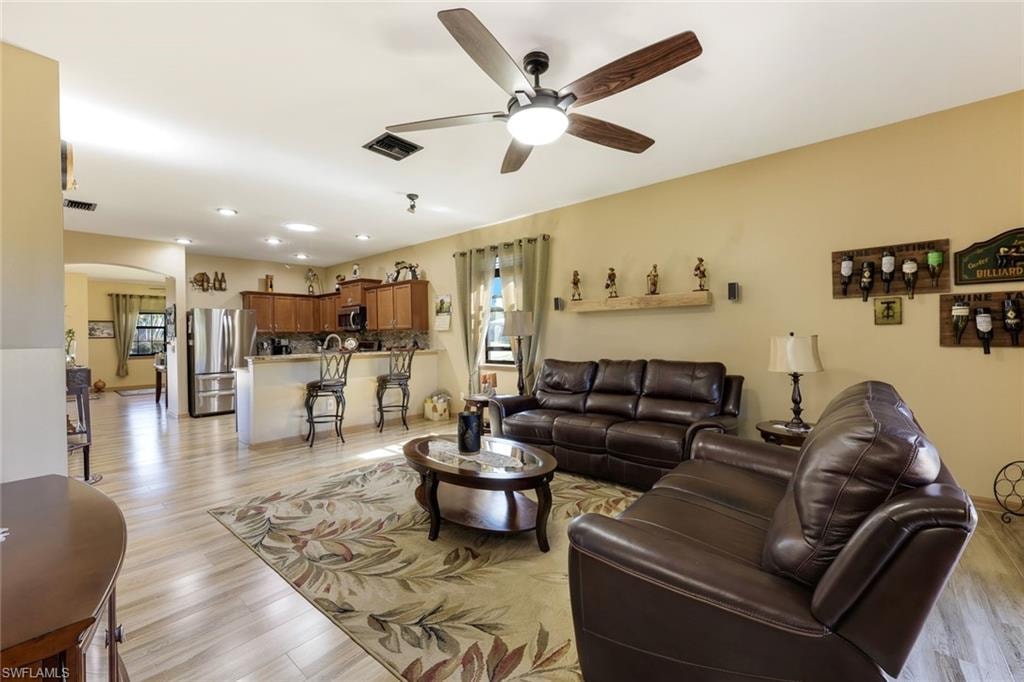 Living area with light wood finished floors and a ceiling fan