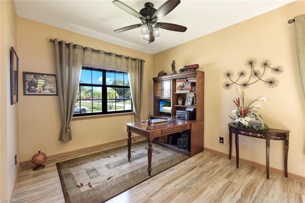 Office area with ceiling fan, light wood finished floors, and a chandelier