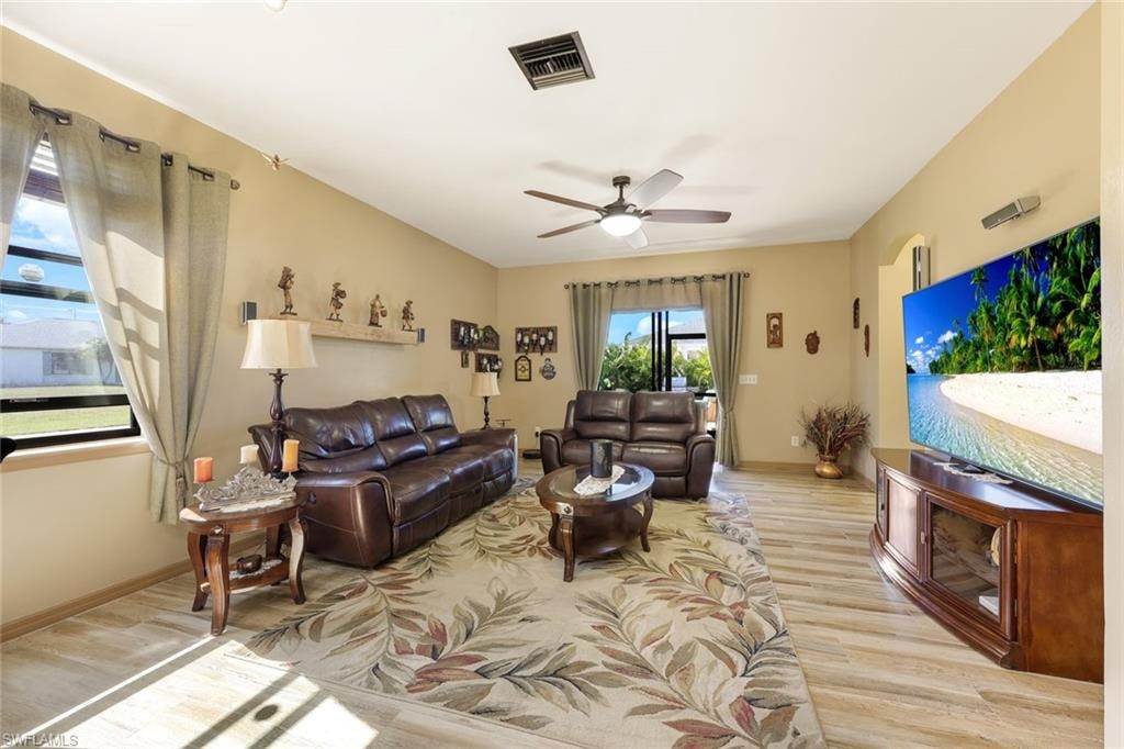 Living area featuring light wood-style floors, a ceiling fan, and arched walkways