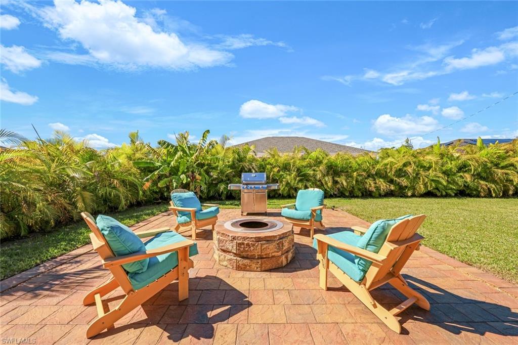 Fenced backyard featuring an outdoor fire pit, a sunroom, grilling area, a patio, and a storage shed