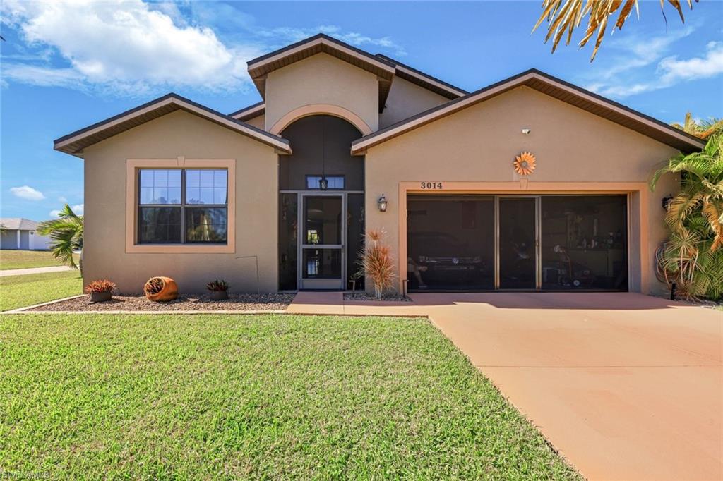 View of front of house featuring a garage, driveway, stucco siding, and a front lawn
