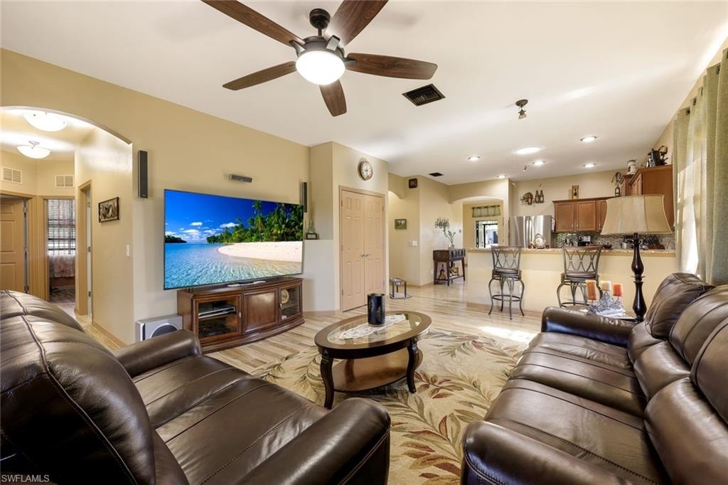 Living area with arched walkways, light wood finished floors, ceiling fan, and recessed lighting