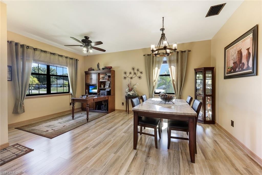 Dining space featuring light wood-type flooring, a chandelier, and a ceiling fan