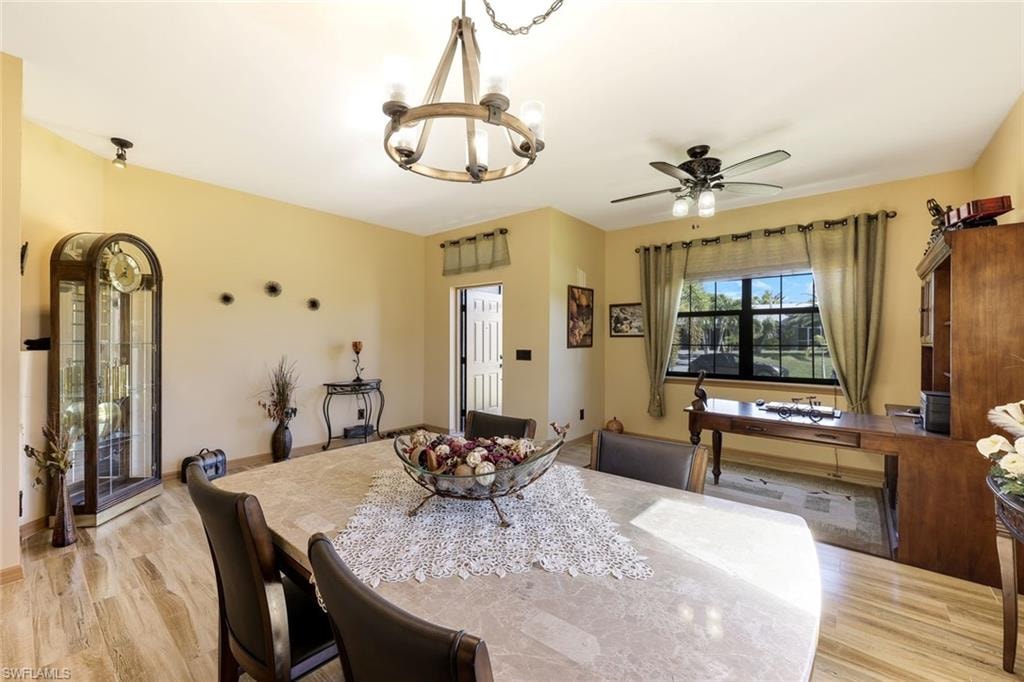 Dining room featuring a ceiling fan, arched walkways, light wood-style floors, and a chandelier
