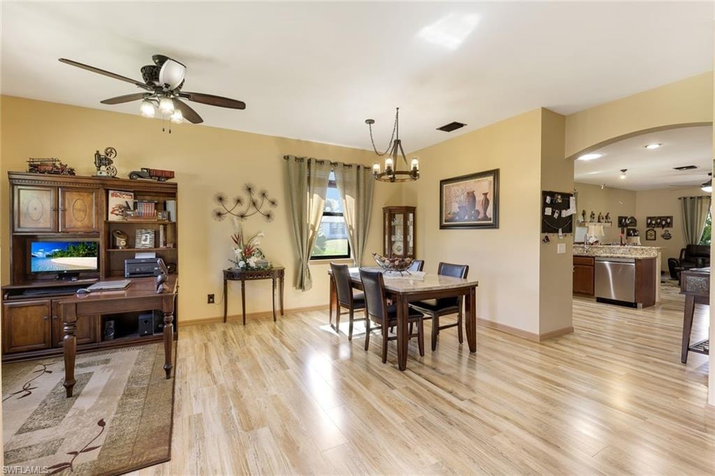 Dining room with arched walkways, a chandelier, light wood-type flooring, and ceiling fan