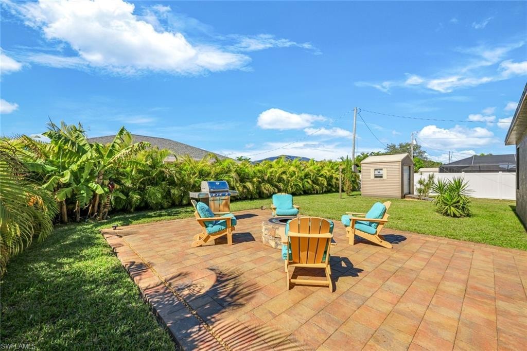 View of green lawn featuring a patio area, an outdoor fire pit, and a sunroom
