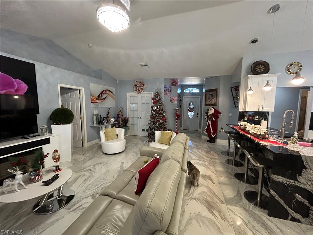 Living room featuring light marble finish flooring and vaulted ceiling