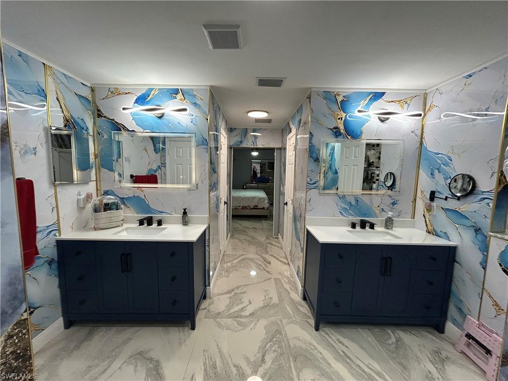 Full bathroom with ensuite bathroom, two vanities, and stone wall