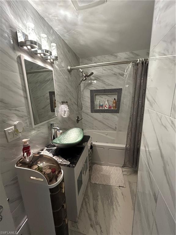 Bathroom featuring tile walls, shower / tub combo with curtain, vanity, and light marble finish floors