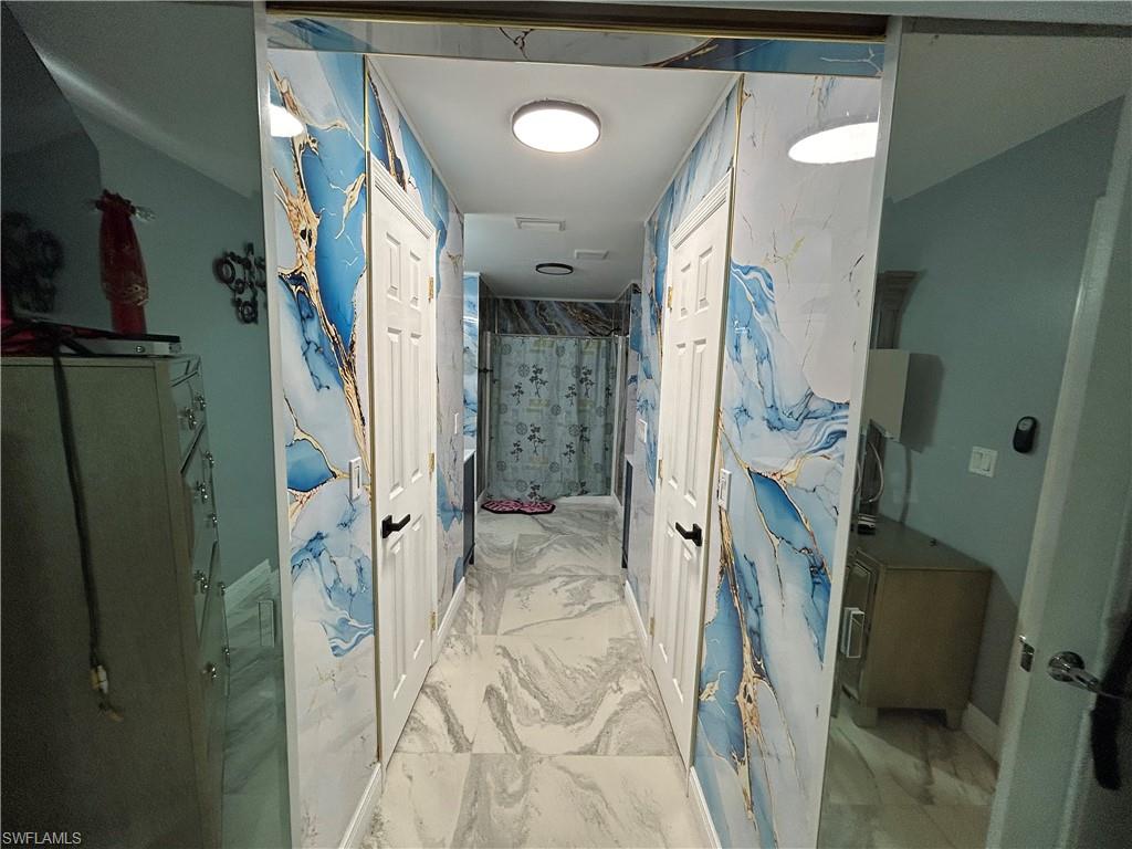 Full bath featuring light marble finish floors and a stall shower