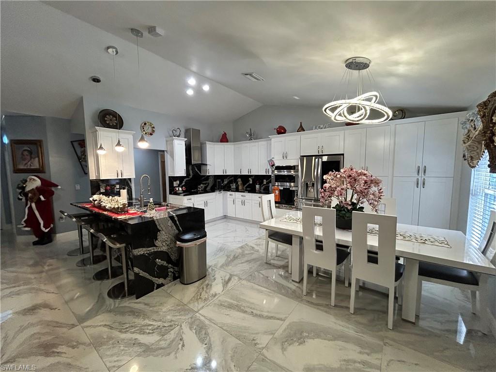 Dining room featuring light marble finish flooring and vaulted ceiling