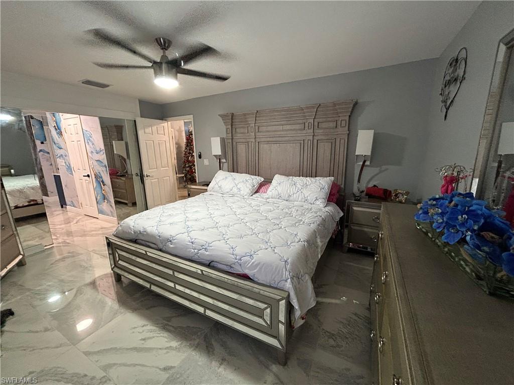Bedroom with marble tiled flooring, a ceiling fan, and a closet