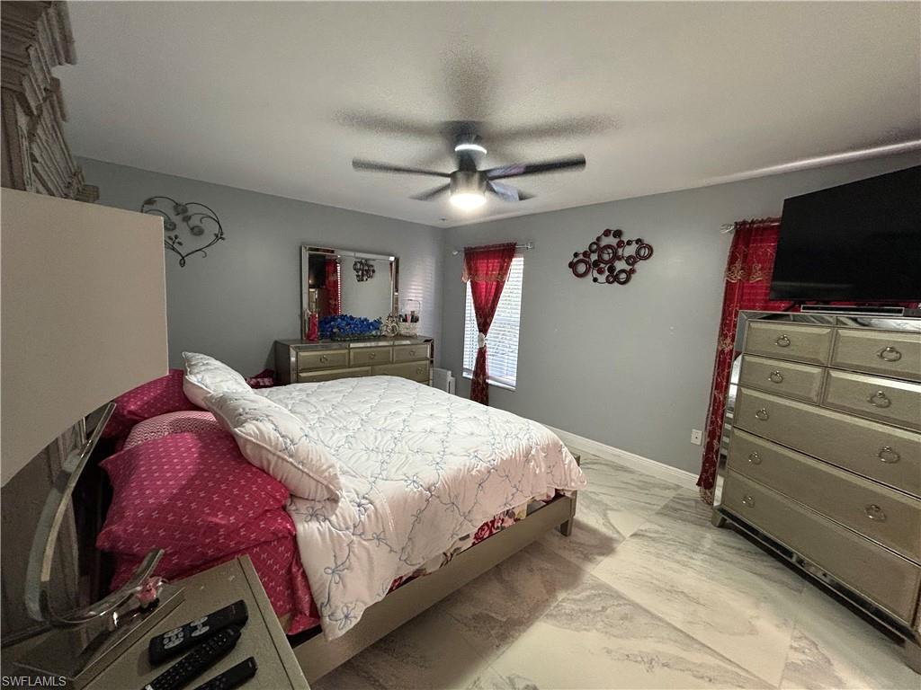 Bedroom with light marble finish flooring, a ceiling fan, and a textured ceiling