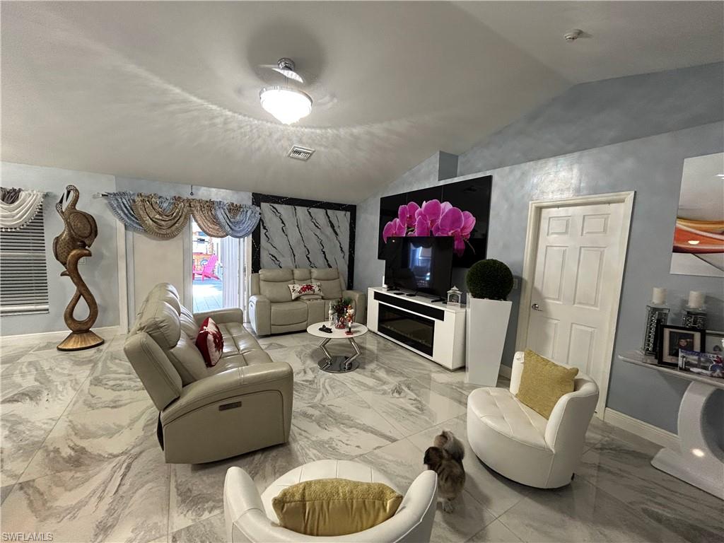 Living room featuring lofted ceiling and light marble finish floors