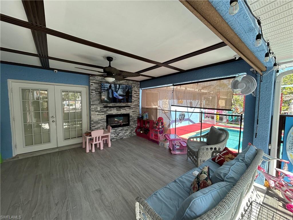 Deck featuring ceiling fan, french doors, and an outdoor living space with a fireplace