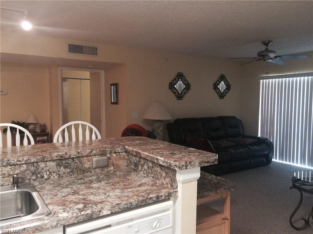 Kitchen featuring white dishwasher, ceiling fan, a textured ceiling, open floor plan, and dark carpet