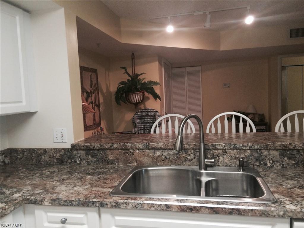 Kitchen with white cabinetry, track lighting, and dark stone counters