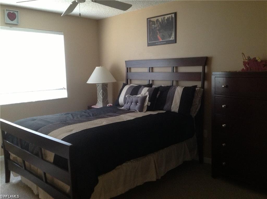 Carpeted bedroom with a textured ceiling and ceiling fan