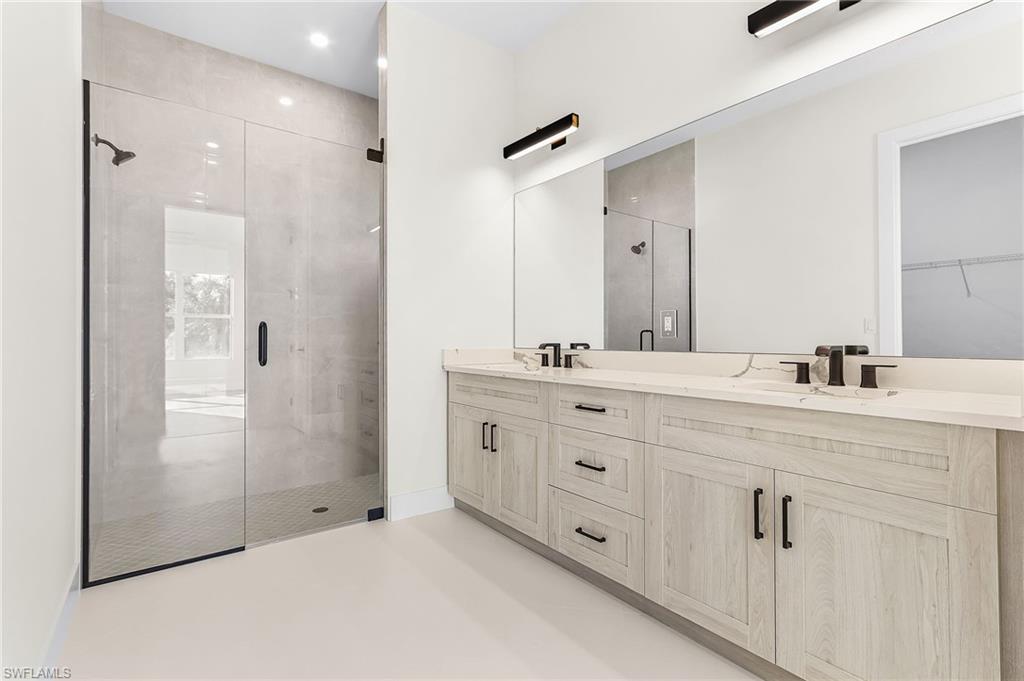 Master Full bath featuring a shower stall, double vanity, and finished concrete flooring