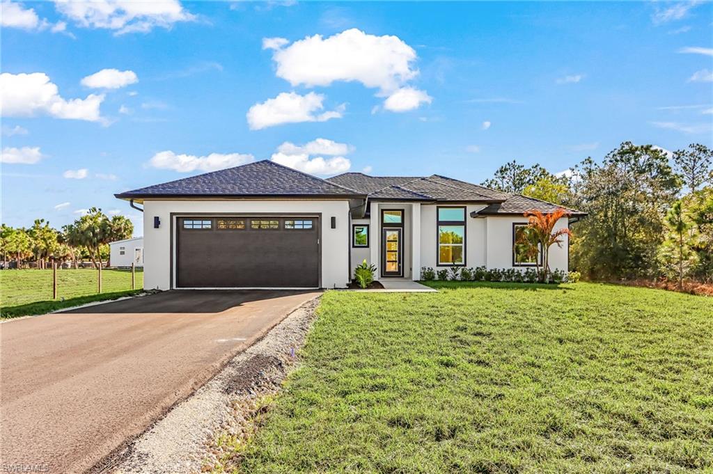 Front of house featuring a front yard, stucco siding, a garage, and asphalt driveway
