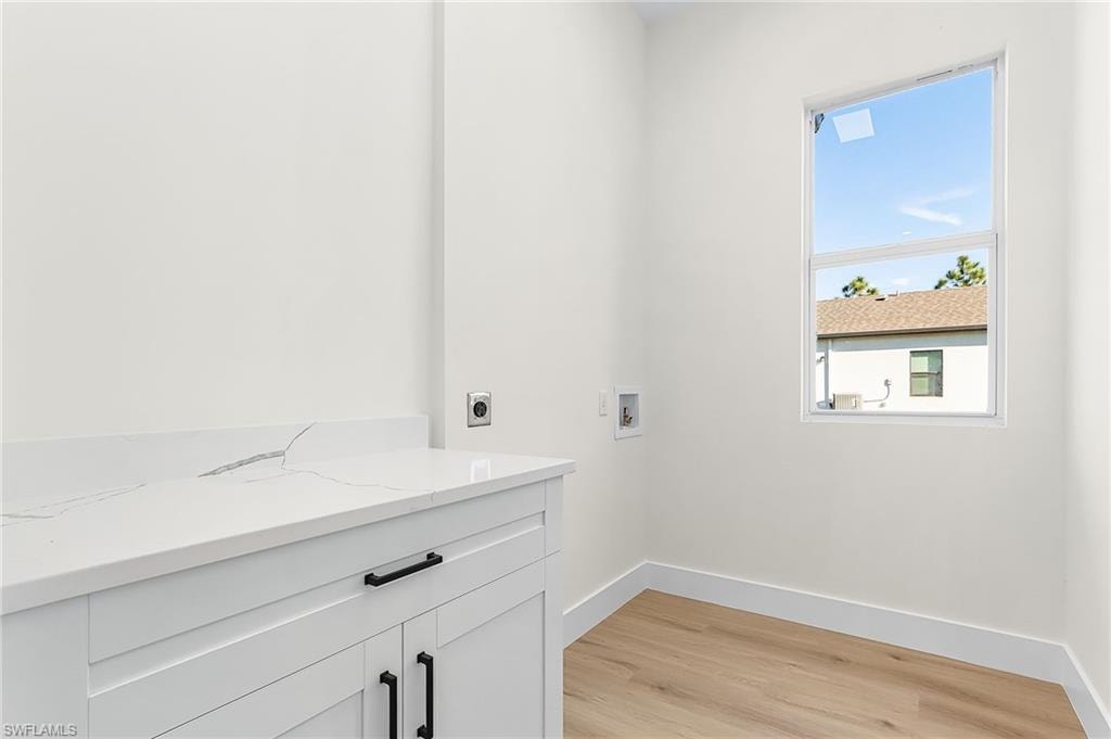 Laundry room featuring hookup for a washing machine, hookup for an electric dryer, light wood-style floors, and cabinet space