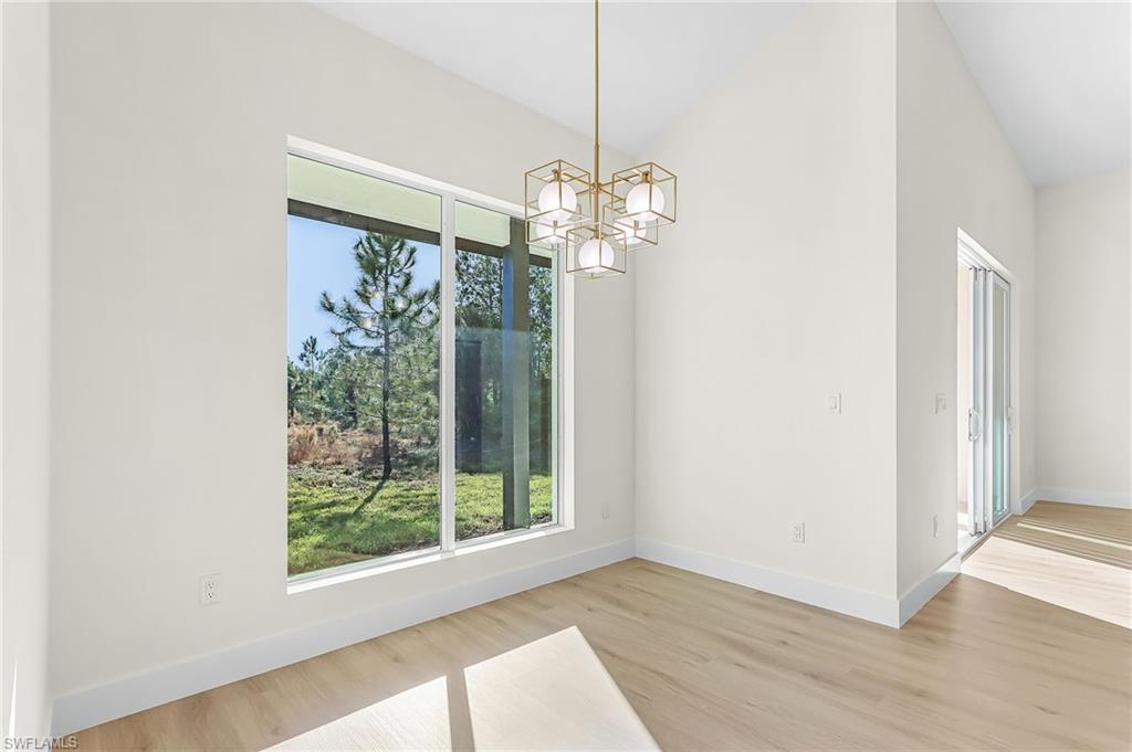 Dining area with suspended lighting, vaulted ceiling, and light wood-type flooring