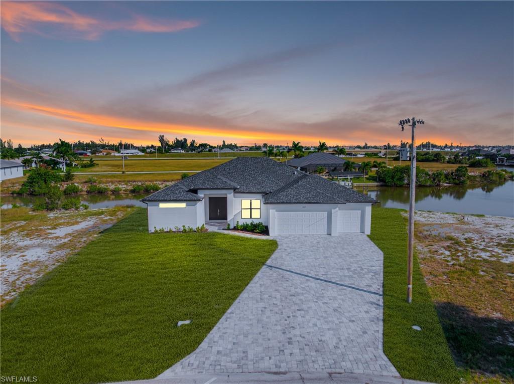 View of front of property featuring an attached garage, a lawn, decorative driveway, and stucco siding