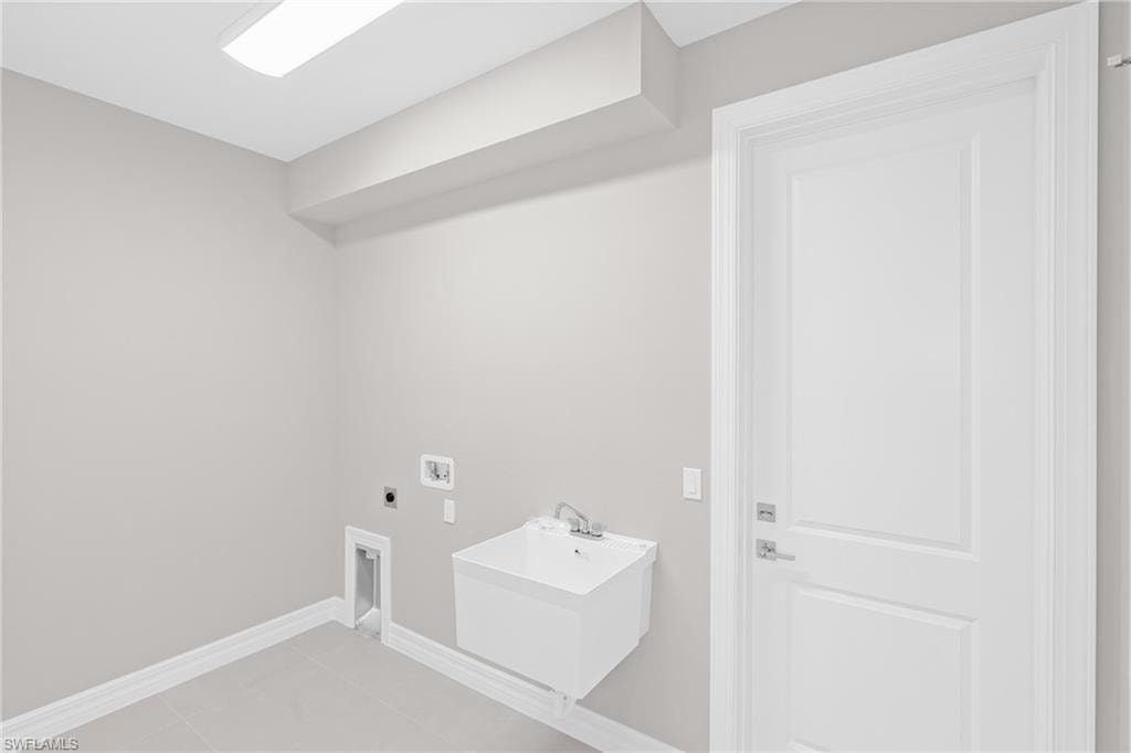 Laundry room featuring electric dryer hookup and light tile patterned floors
