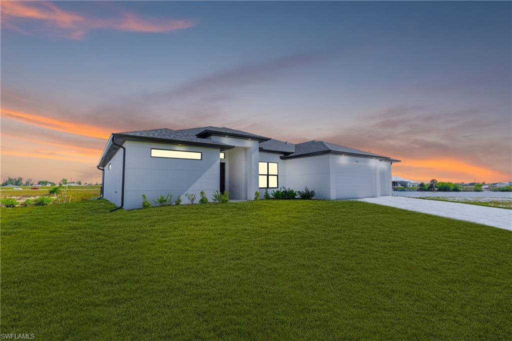View of front of home featuring driveway, a lawn, stucco siding, an attached garage, and a shingled roof