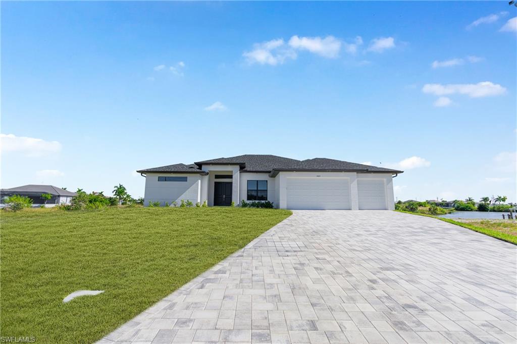 Prairie-style home with an attached garage, a front yard, decorative driveway, and stucco siding