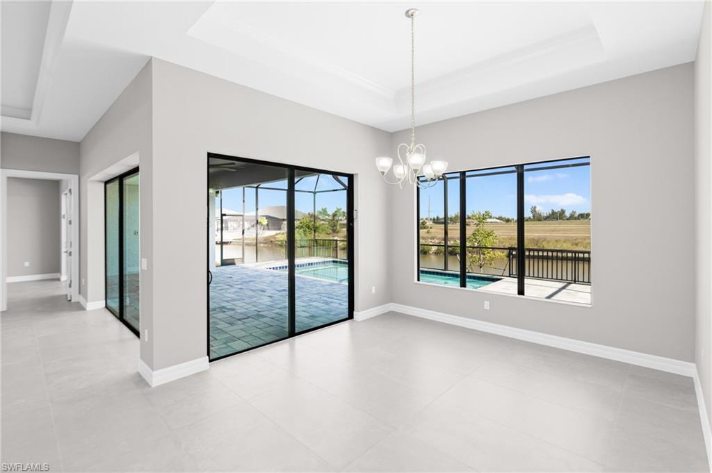 Empty room with a raised ceiling, a chandelier, and a water view