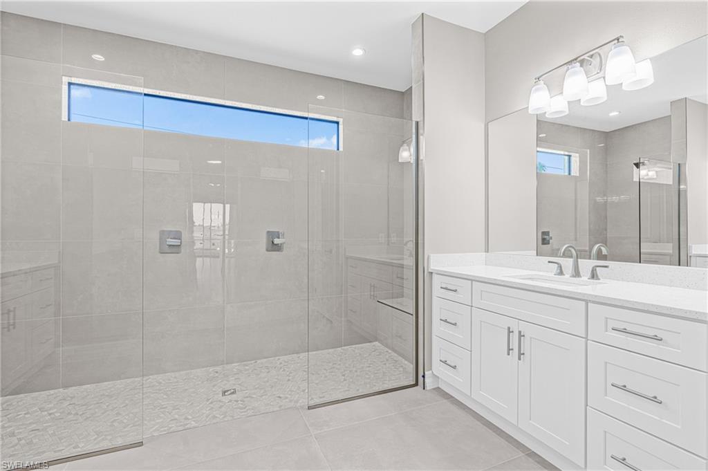 Bathroom featuring light tile patterned floors, vanity, and a walk in shower