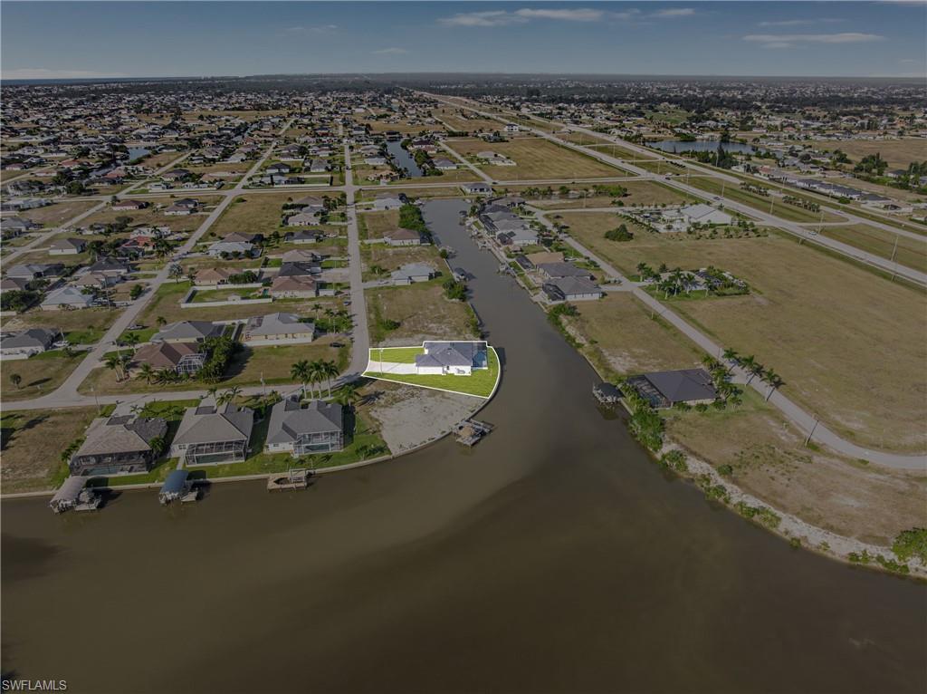 Aerial view of property and surrounding area featuring a nearby body of water and nearby suburban area