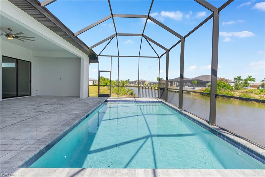 Swimming pool featuring ceiling fan, a sunroom, a water view, and a lanai