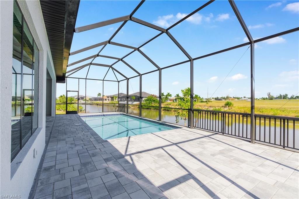 Outdoor pool with a sunroom, a water view, a lanai, and a patio